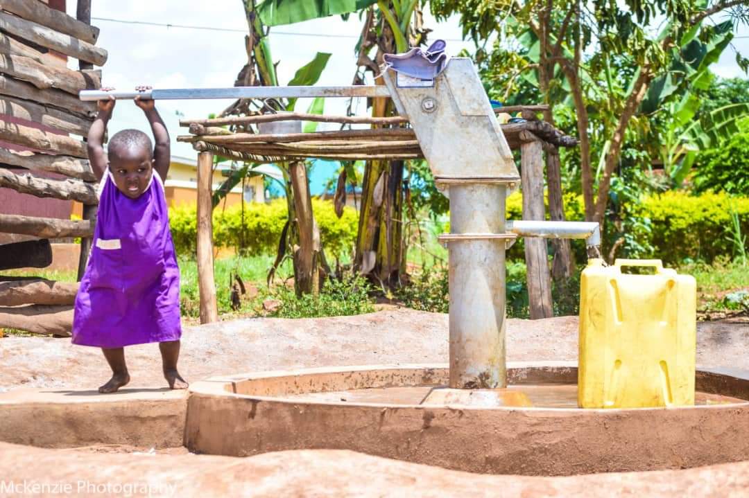 A girl pumping water at a borehole