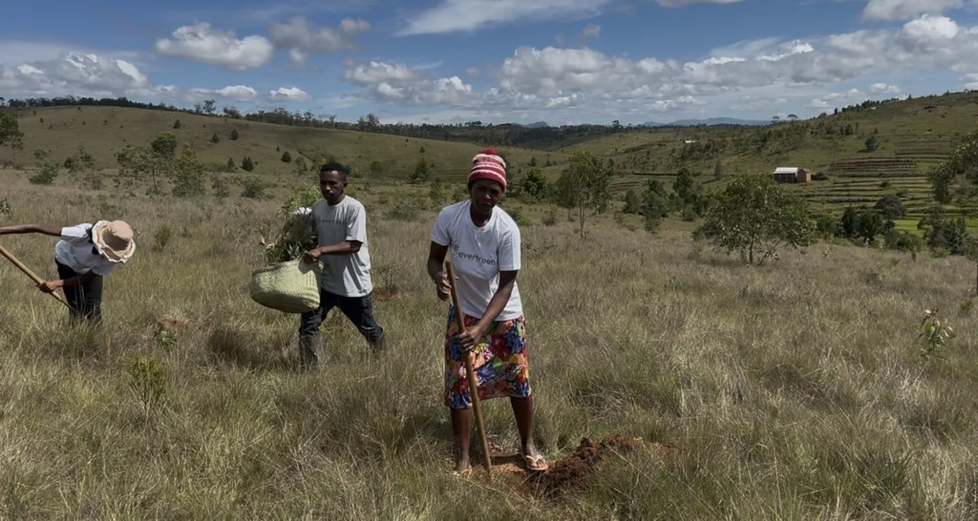 Vohidahy villagers on a forest trail carrying tools and seedling trays