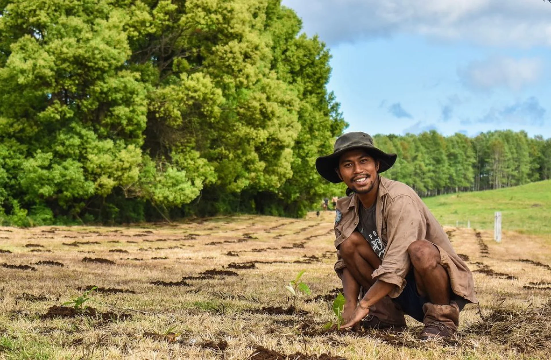 Volunteer James planting a native tree seedling at the Queensland restoration site
